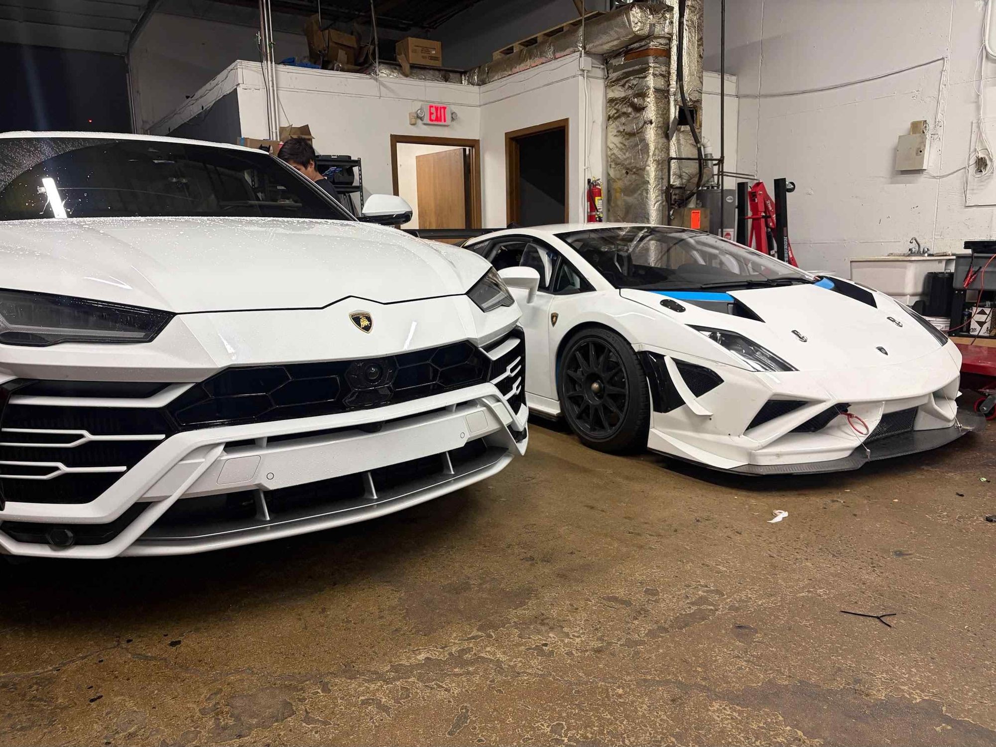 White Urus and Huracán side by side in the shop