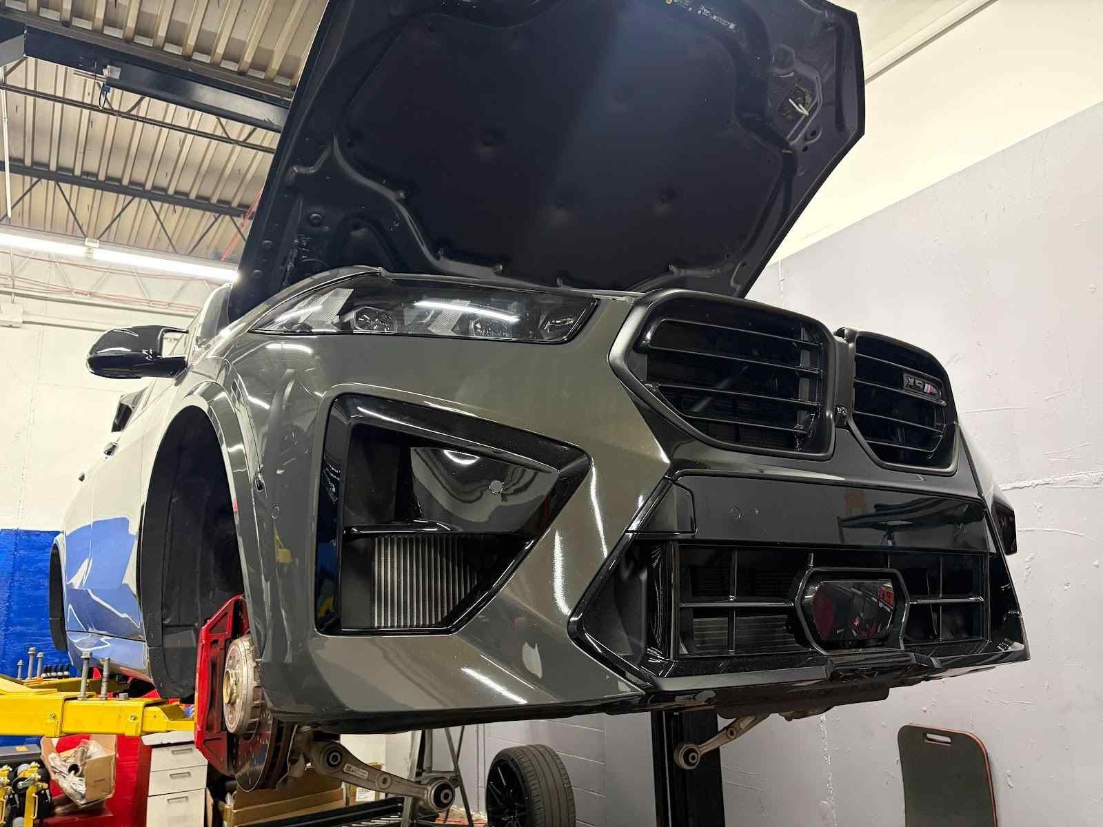 Technician under the hood of a BMW on the lift